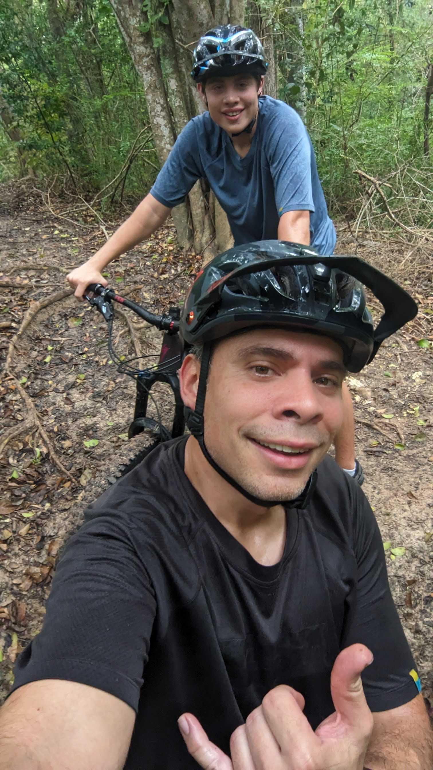 Erich and Matthew Gellert taking a mountain bike break on a wooded trail.